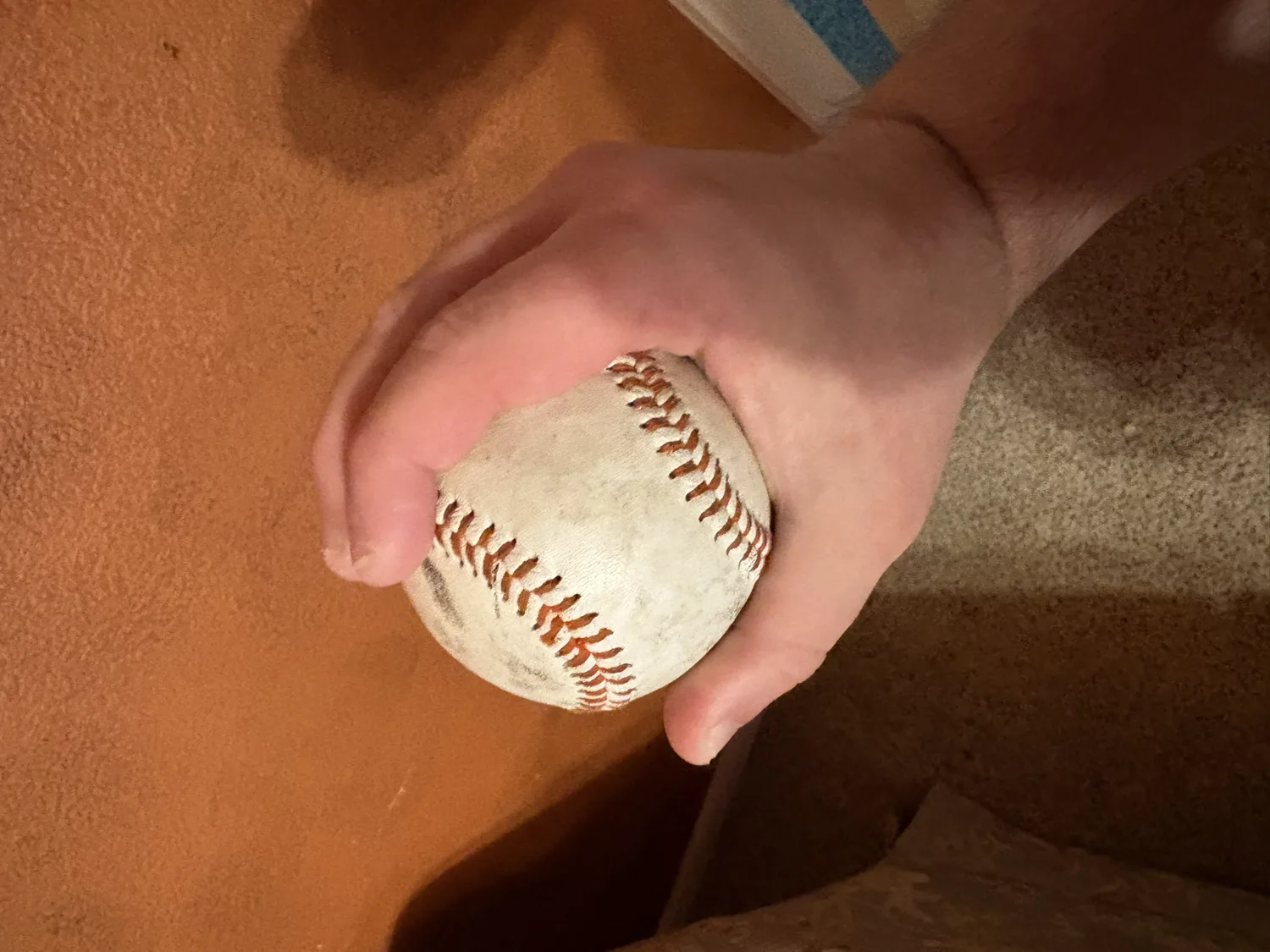 A side view of a football-change grip with the ball set deep in the palm under four fingers.