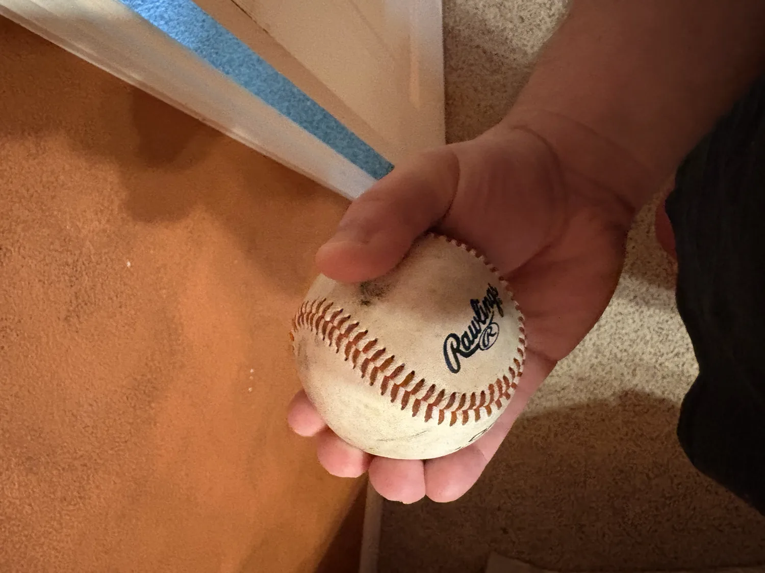 A hand gripping a baseball with all four fingers together across the top, the football change or palmball grip.